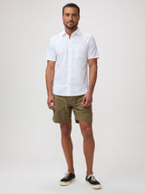 Man wearing a white short-sleeve shirt and green shorts | breathable button up shirts