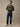 Man wearing an army green long-sleeve flannel shirt, dark blue jeans, and white sneakers, standing. Layers clean under flannel, fleece, or a shell jacket