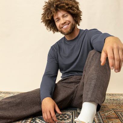 Man sitting on a rug wearing a blue long sleeve t-shirt and pants | Fresh Clean Threads